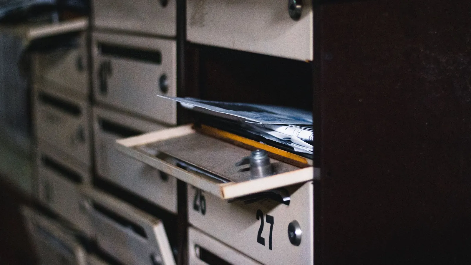 Open apartment mailbox door with a stack of unopened letters inside