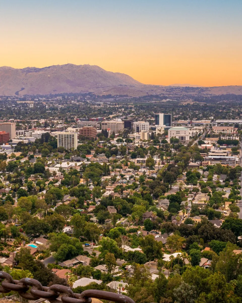 Downtown Riverside, CA and tree-filled neighborhoods below the mountains at sunset