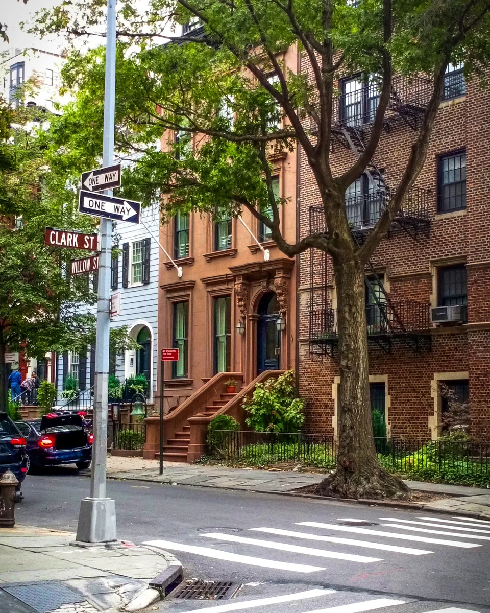 Brownstones and a tree-lined corner at Clark Street and Willow Street in Brooklyn, NY