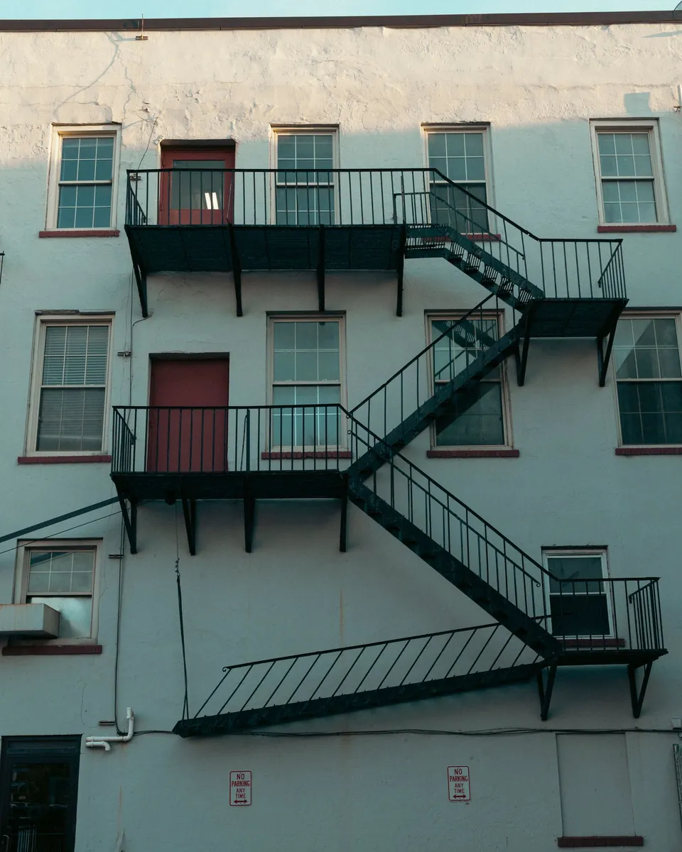 Black iron fire escape on the pale facade of a historic building in Rochester, NY