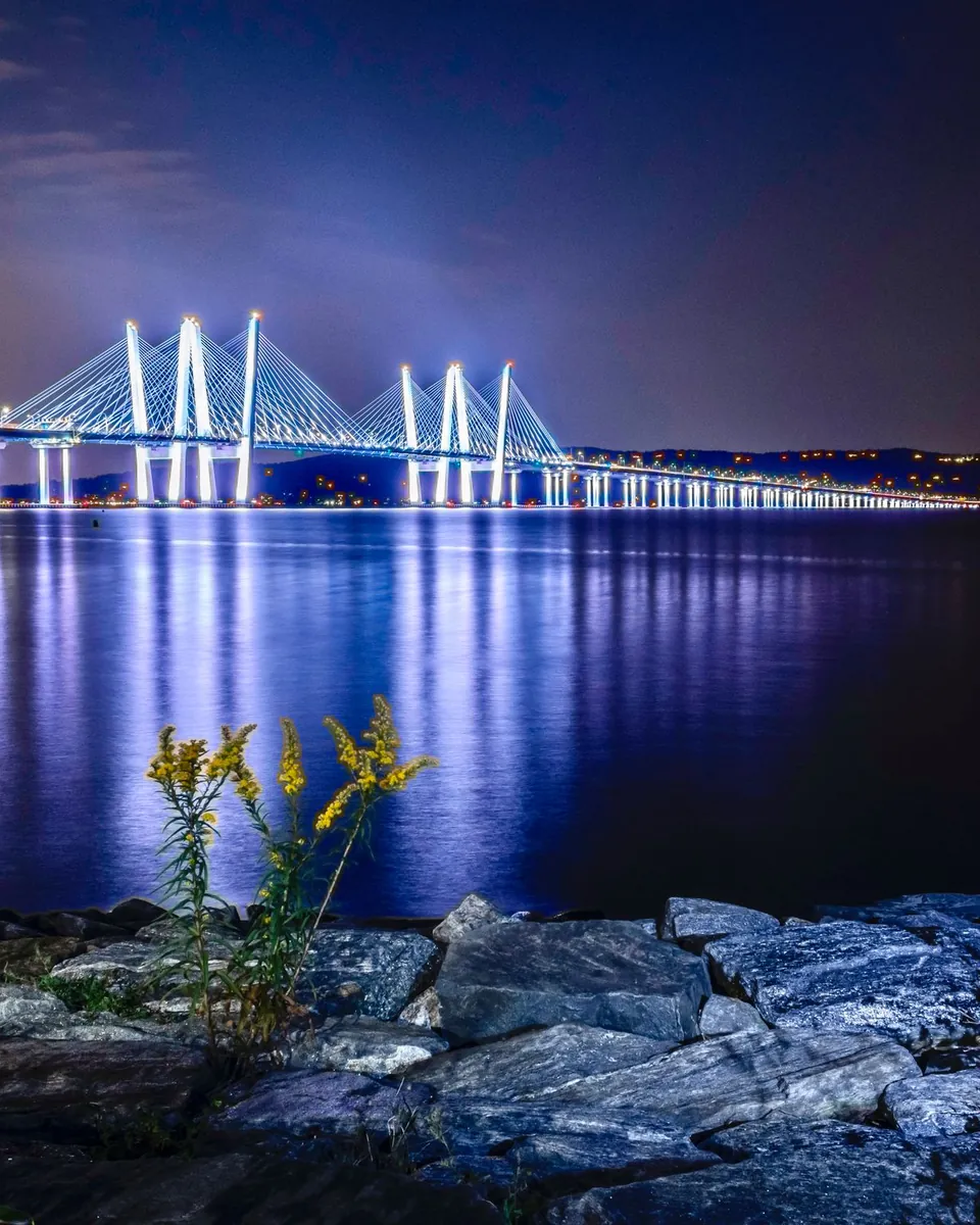 Hudson River bridge lit up at night, seen from the shore at Tarrytown, NY in Westchester County