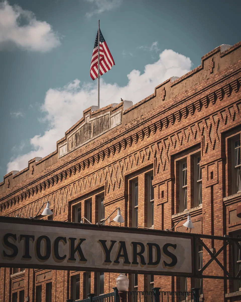Historic Stockyards building and STOCK YARDS sign in Fort Worth, TX with an American flag
