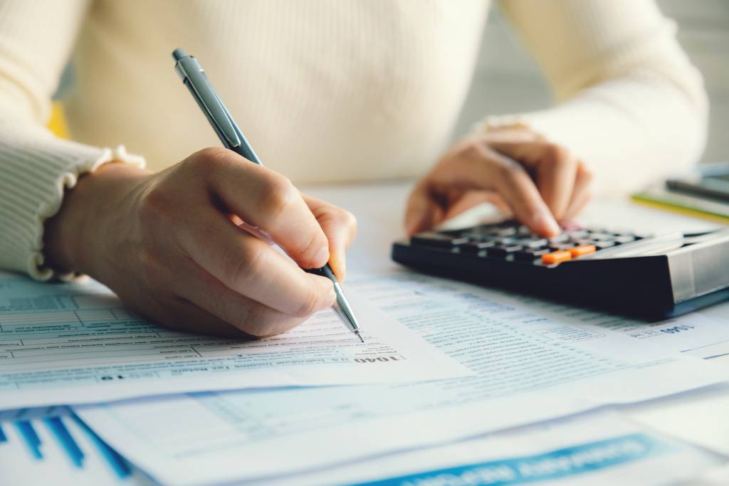 Closeup of woman using calculator and completing a tax return document