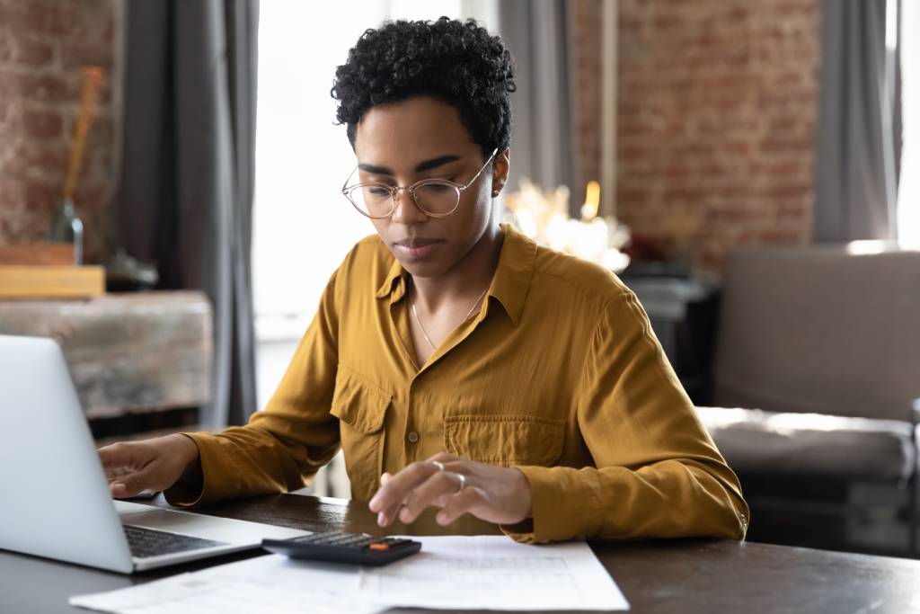 Young woman calculating tax bill in modern office setting