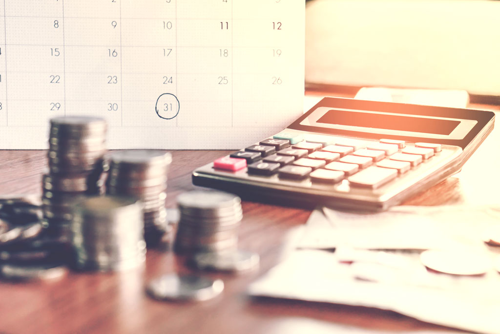 Calendar in background calculator and coins in foreground for tax season